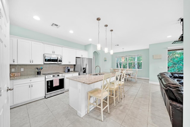 kitchen featuring appliances with stainless steel finishes, a center island with sink, and white cabinets