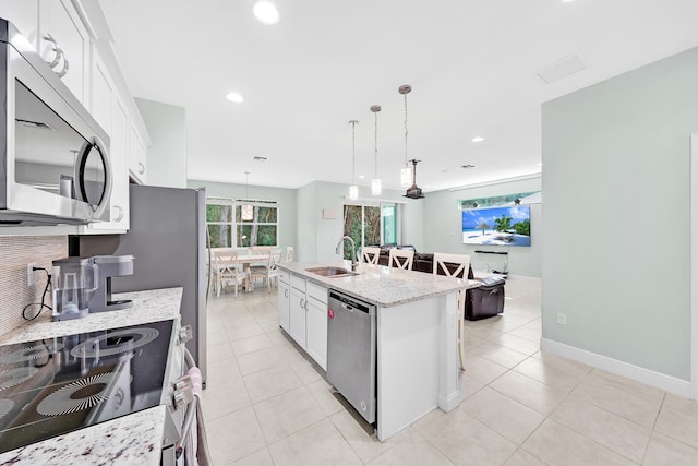 kitchen with white cabinetry, stainless steel appliances, a kitchen island with sink, and hanging light fixtures