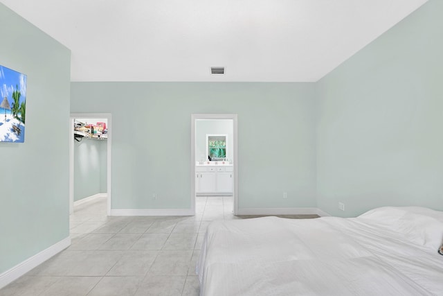 unfurnished bedroom featuring light tile patterned flooring, a walk in closet, and ensuite bath