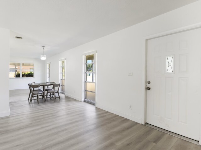 foyer entrance featuring light wood-style floors, baseboards, visible vents, and a wealth of natural light