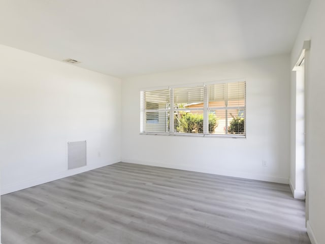 unfurnished room featuring wood finished floors, visible vents, and baseboards