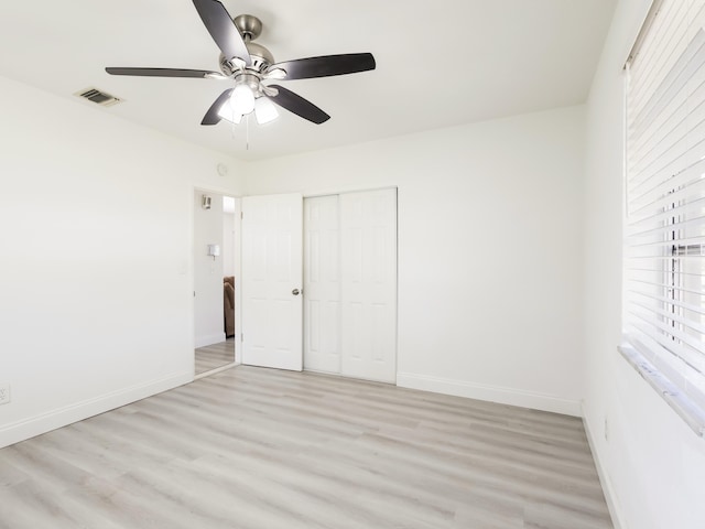 unfurnished bedroom featuring baseboards, visible vents, light wood-style floors, and a closet