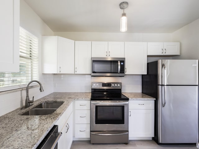 kitchen with decorative backsplash, appliances with stainless steel finishes, white cabinetry, and a sink