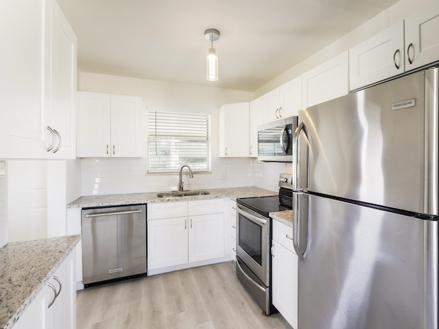 kitchen featuring light wood finished floors, a sink, tasteful backsplash, white cabinetry, and appliances with stainless steel finishes