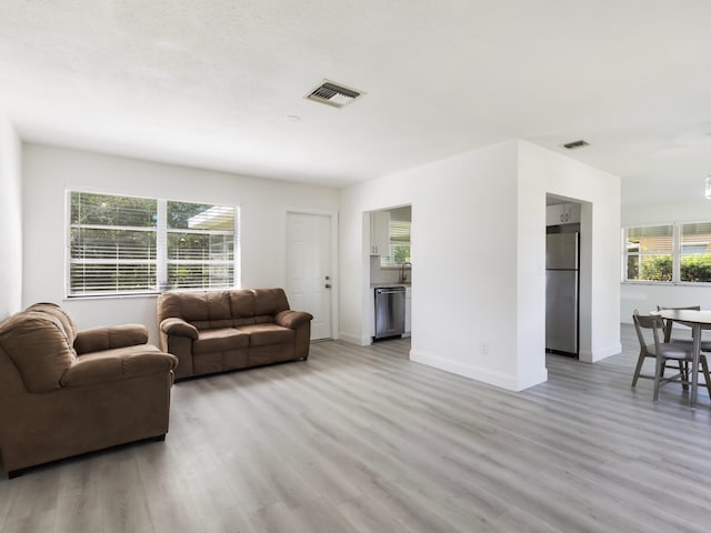 living area featuring wood finished floors, visible vents, and a healthy amount of sunlight
