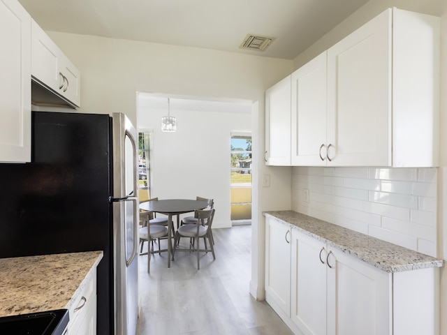 kitchen with white cabinets, light wood-style flooring, tasteful backsplash, visible vents, and freestanding refrigerator