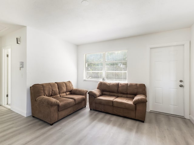 living area featuring attic access, baseboards, and light wood-style floors