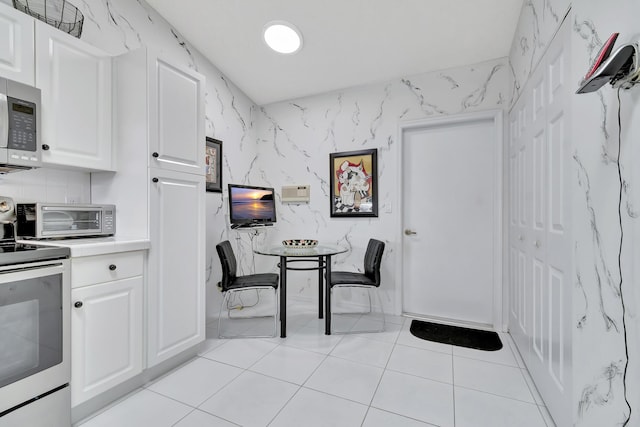 kitchen with stainless steel appliances, white cabinetry, and light tile patterned floors