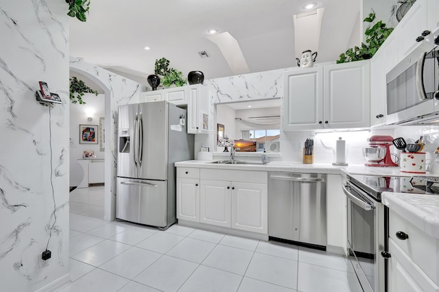 kitchen featuring appliances with stainless steel finishes, sink, light tile patterned floors, and white cabinets