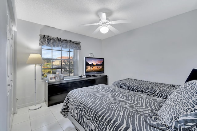 bedroom featuring ceiling fan, a textured ceiling, and light tile patterned floors