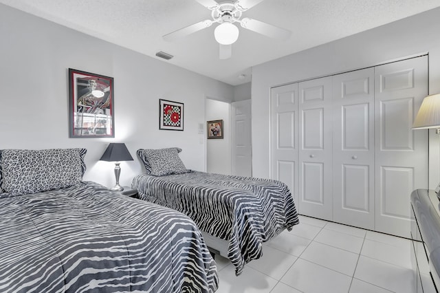 bedroom featuring ceiling fan, a textured ceiling, a closet, and light tile patterned floors