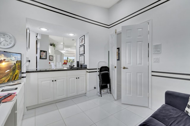 kitchen featuring dark stone countertops, light tile patterned floors, and white cabinets