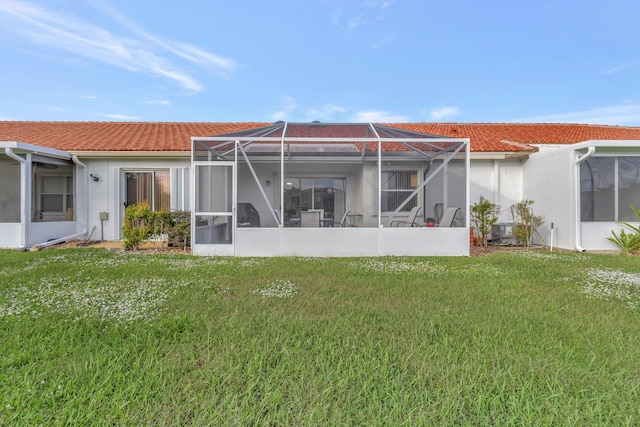 rear view of property with a lanai and a lawn