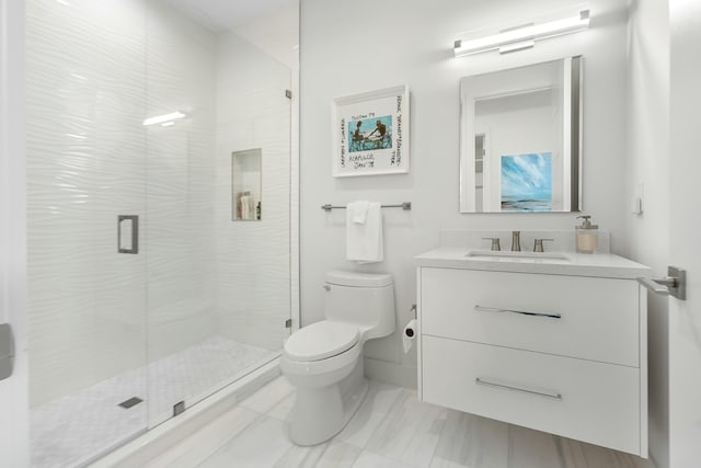 bathroom featuring vanity, a shower with shower door, and toilet