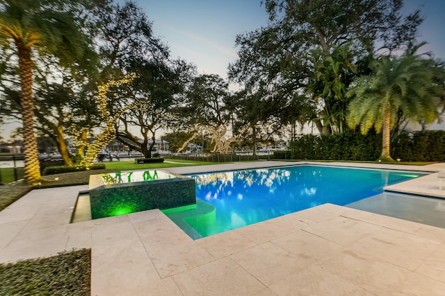 pool at dusk featuring a patio area