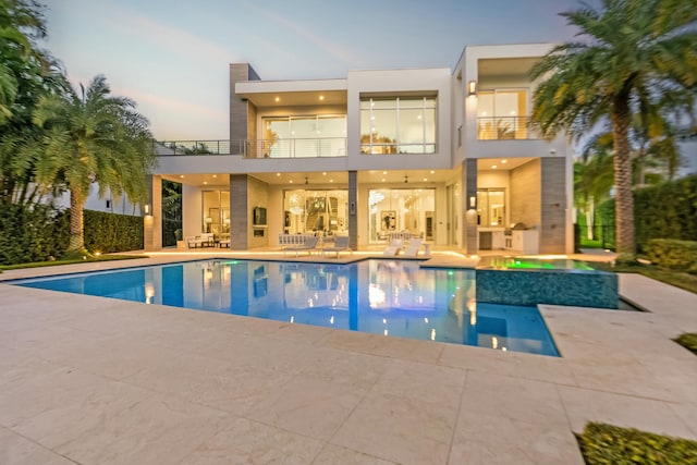 pool at dusk featuring a hot tub and a patio area