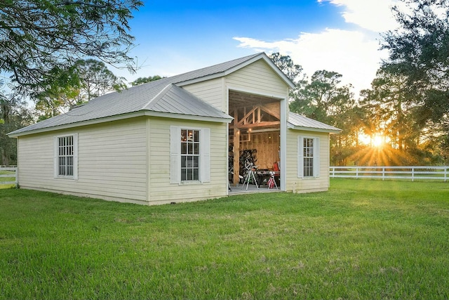 rear view of property featuring metal roof, fence, an outdoor structure, and a yard
