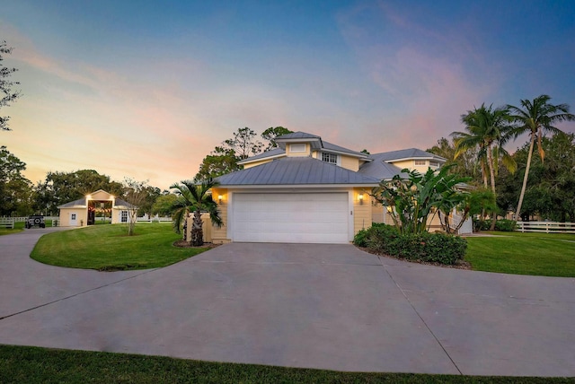 view of front facade featuring a lawn, an attached garage, a standing seam roof, metal roof, and driveway