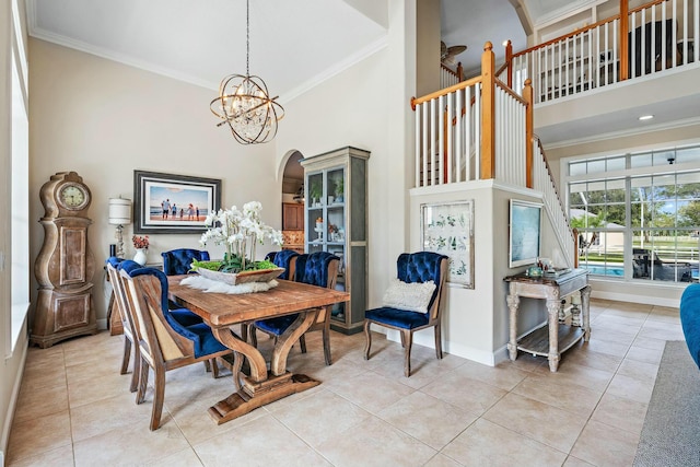 dining area featuring arched walkways, light tile patterned floors, a high ceiling, ornamental molding, and an inviting chandelier