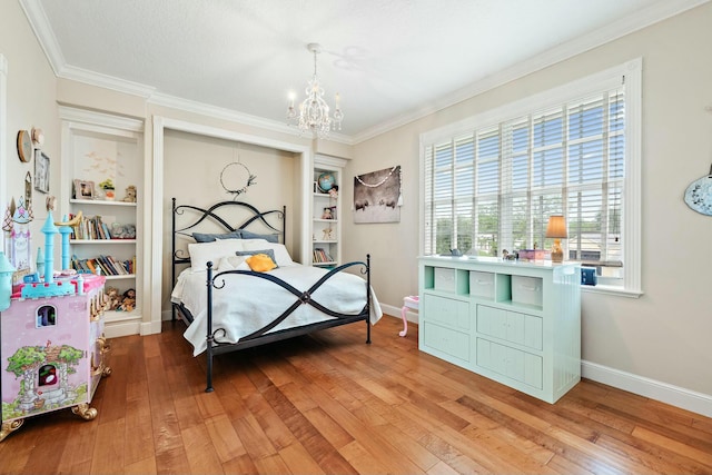 bedroom featuring crown molding, baseboards, hardwood / wood-style flooring, and an inviting chandelier