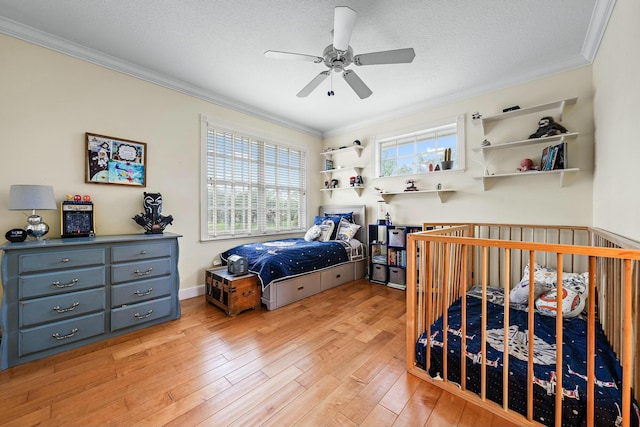 bedroom with a textured ceiling, ceiling fan, light wood-style flooring, baseboards, and crown molding
