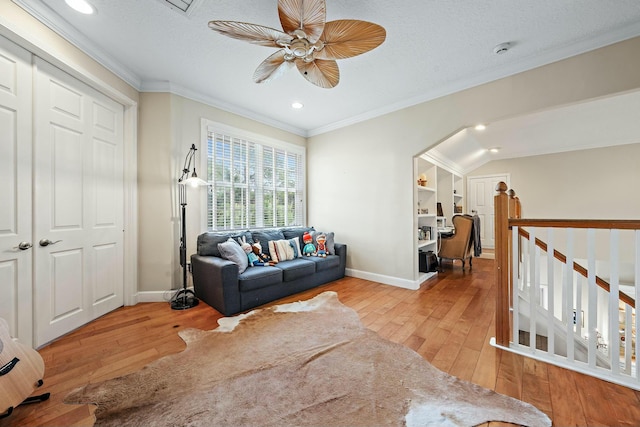 living area featuring a textured ceiling, baseboards, hardwood / wood-style flooring, and crown molding