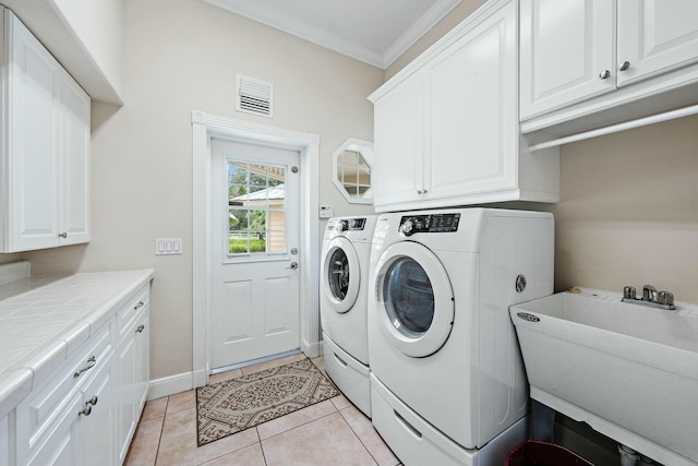 laundry room featuring a sink, visible vents, ornamental molding, cabinet space, and washing machine and clothes dryer