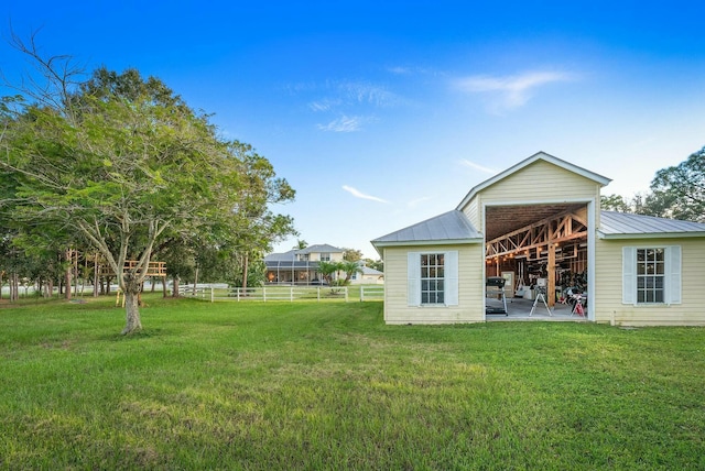 back of property with metal roof, a yard, an outdoor structure, and fence
