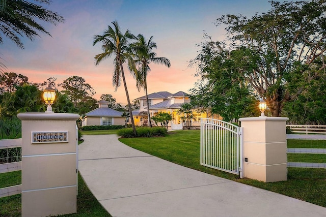 view of front of home with a fenced front yard, a gate, and a lawn