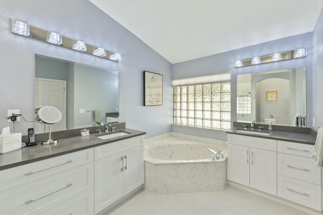 bathroom featuring tile patterned flooring, vanity, a relaxing tiled tub, and lofted ceiling