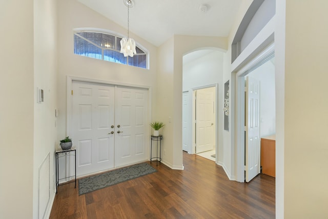 entrance foyer featuring a notable chandelier, dark wood-type flooring, and high vaulted ceiling