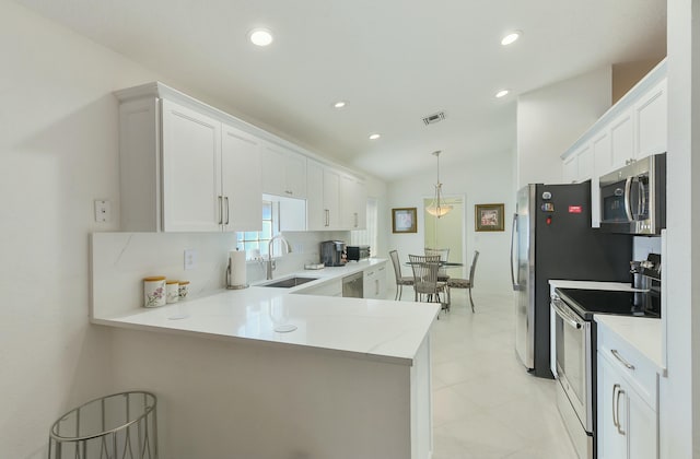 kitchen with white cabinetry, sink, stainless steel appliances, and kitchen peninsula