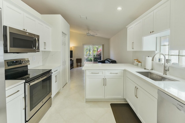 kitchen with sink, white cabinetry, appliances with stainless steel finishes, kitchen peninsula, and backsplash