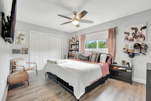 bedroom with ceiling fan, light hardwood / wood-style floors, a closet, and a textured ceiling