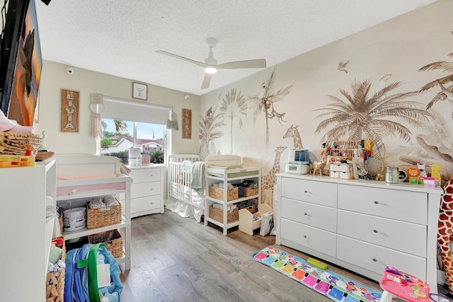 bedroom featuring ceiling fan, light hardwood / wood-style floors, and a textured ceiling