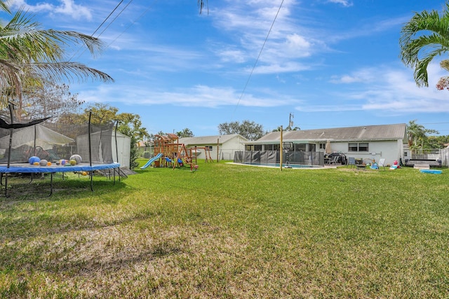 view of yard with a shed, a fenced in pool, a playground, and a trampoline