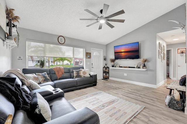 living room featuring vaulted ceiling, a textured ceiling, ceiling fan, and light hardwood / wood-style flooring