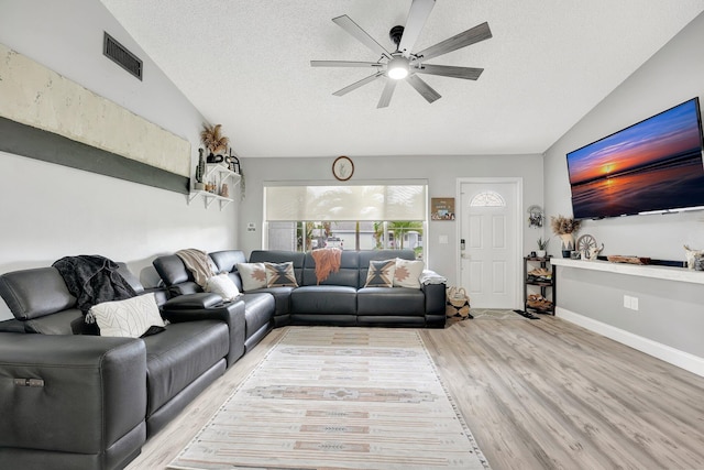 living room with vaulted ceiling, a textured ceiling, and light wood-type flooring