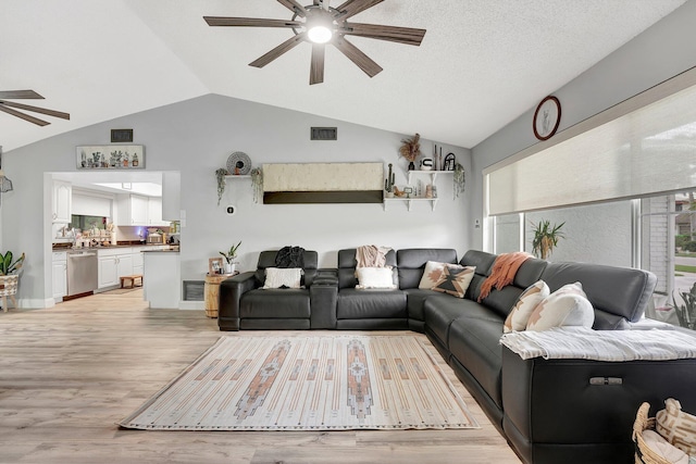 living room with lofted ceiling, a textured ceiling, light hardwood / wood-style flooring, and ceiling fan