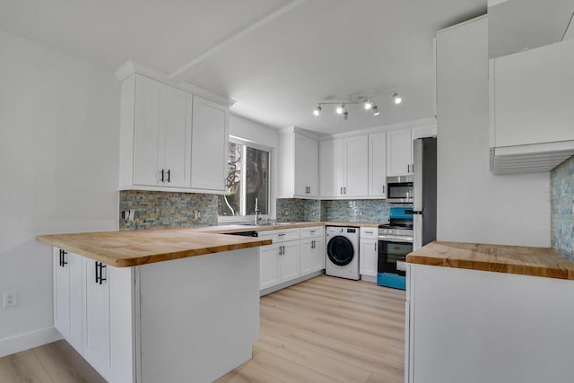 kitchen with stainless steel appliances, butcher block counters, washer / clothes dryer, decorative backsplash, and light wood finished floors