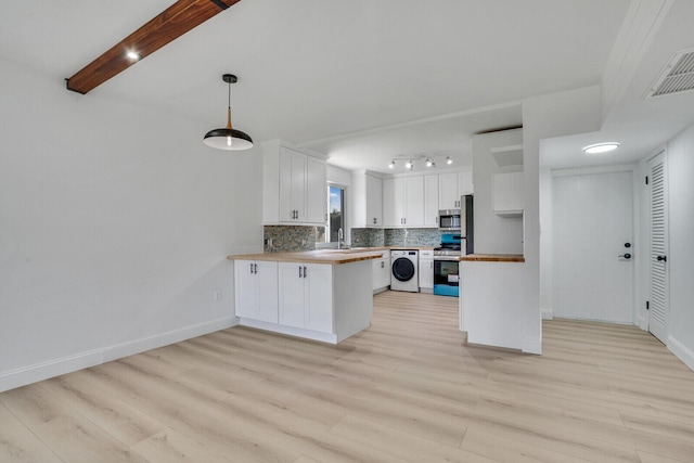 kitchen with a peninsula, a sink, appliances with stainless steel finishes, decorative backsplash, and washer / dryer