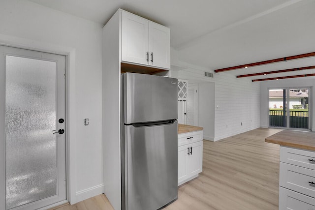 kitchen with visible vents, freestanding refrigerator, wood counters, light wood-type flooring, and beamed ceiling