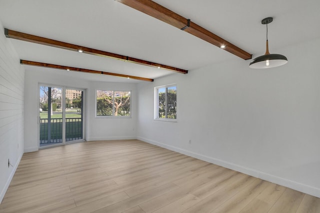 spare room with light wood finished floors, baseboards, and beamed ceiling