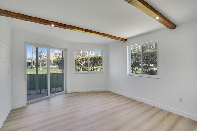 unfurnished room with beam ceiling, a healthy amount of sunlight, baseboards, and wood finished floors