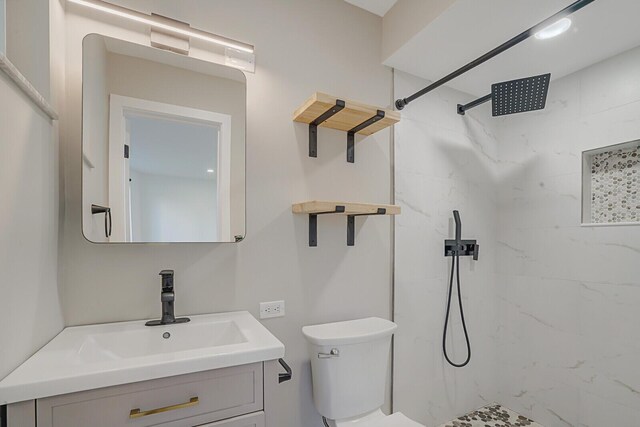 bathroom featuring toilet, vanity, and a marble finish shower