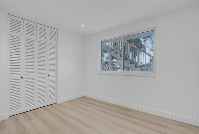 unfurnished bedroom with light wood-type flooring, baseboards, and a closet