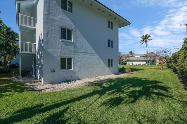 view of side of home with a lawn and stucco siding