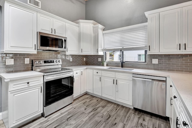 kitchen with tasteful backsplash, sink, stainless steel appliances, and white cabinets