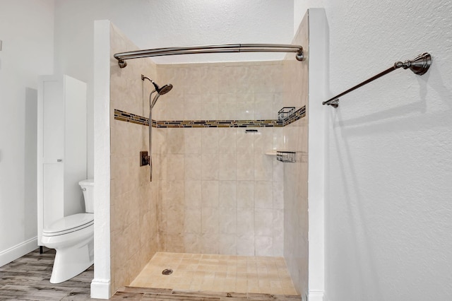 bathroom featuring tiled shower, toilet, and hardwood / wood-style floors