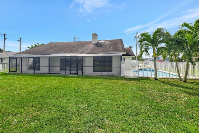 rear view of property with a fenced in pool and a yard